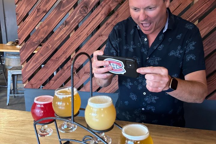a man sitting at a table with a flight of beer